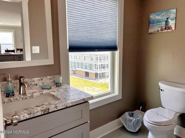 bathroom featuring toilet, vanity, a wealth of natural light, and baseboards