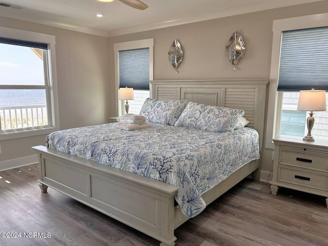 bedroom with ornamental molding, dark wood-style flooring, a water view, and visible vents