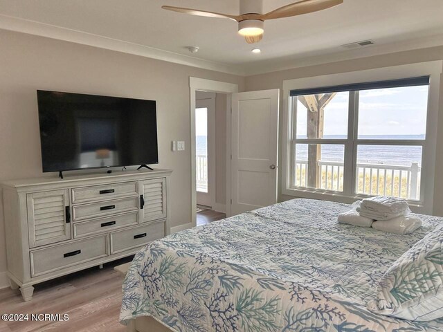 bedroom featuring visible vents, baseboards, a ceiling fan, a water view, and light wood-type flooring