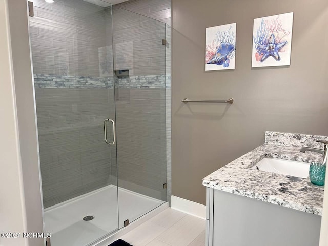 bathroom with a stall shower, vanity, and baseboards