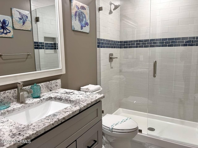 full bathroom featuring a stall shower, vanity, and toilet