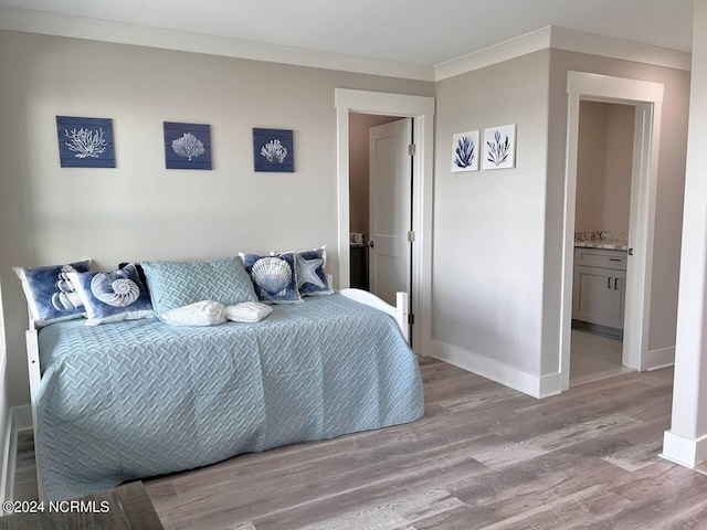 bedroom featuring light wood-style floors, connected bathroom, ornamental molding, and baseboards