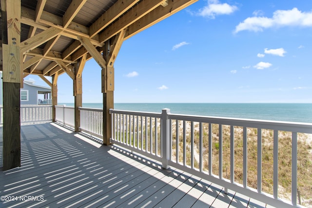 wooden deck featuring a beach view and a water view