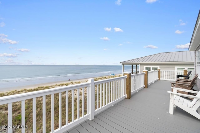 wooden deck featuring a beach view and a water view