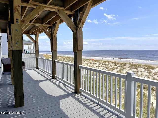 wooden deck with a water view and a beach view