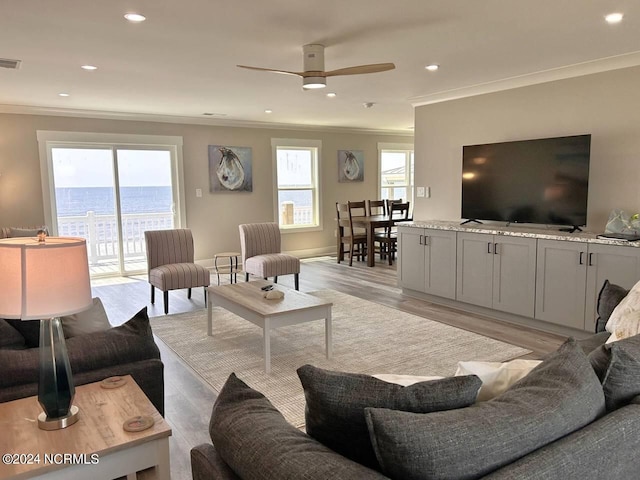 living area featuring recessed lighting, a water view, light wood-style flooring, ornamental molding, and a ceiling fan