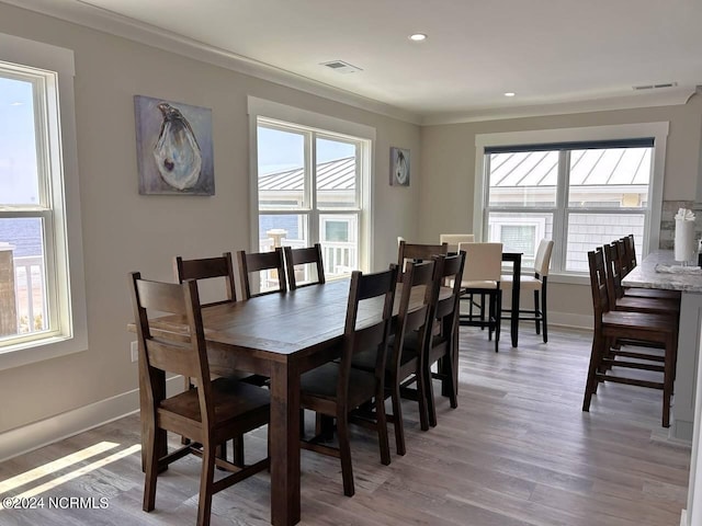 dining area with a healthy amount of sunlight, visible vents, and crown molding