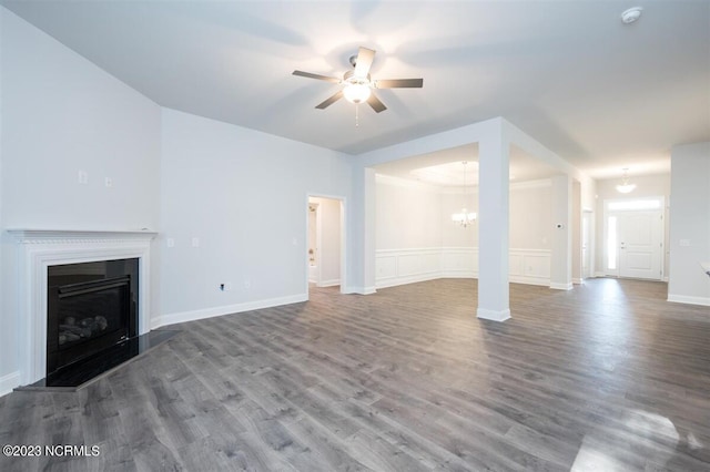 unfurnished living room featuring ceiling fan with notable chandelier, ornamental molding, and hardwood / wood-style floors