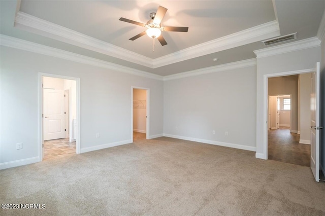 unfurnished bedroom with crown molding, a spacious closet, light carpet, and ceiling fan