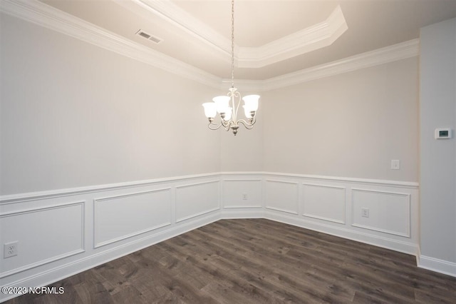 empty room featuring a raised ceiling, crown molding, dark wood-type flooring, and an inviting chandelier