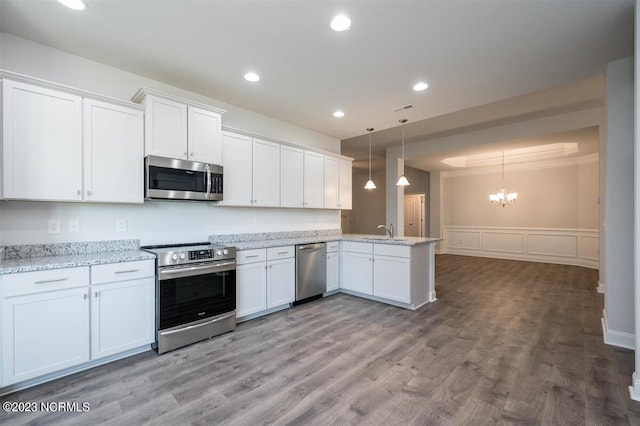 kitchen with pendant lighting, sink, appliances with stainless steel finishes, white cabinetry, and kitchen peninsula