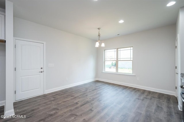 empty room featuring dark wood-type flooring and a chandelier