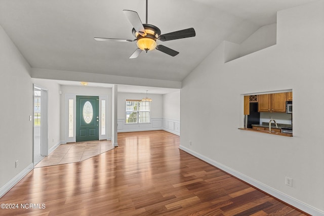 foyer featuring lofted ceiling, ceiling fan with notable chandelier, and light hardwood / wood-style flooring