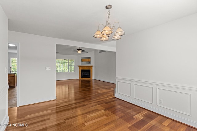 unfurnished living room featuring hardwood / wood-style flooring, plenty of natural light, sink, and ceiling fan with notable chandelier