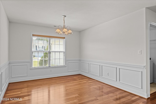 unfurnished room with a notable chandelier and light wood-type flooring