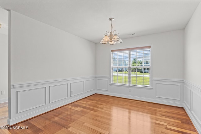 unfurnished room with light wood-type flooring and a chandelier