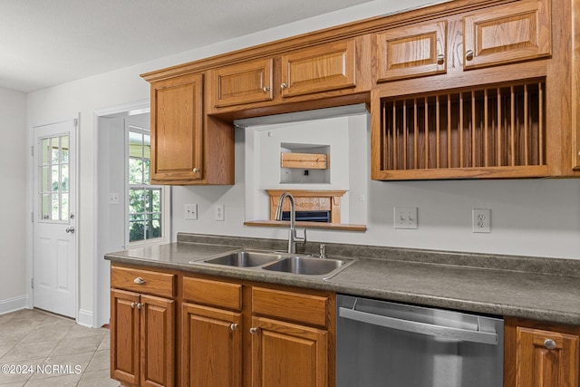 kitchen with light tile patterned flooring, stainless steel dishwasher, and sink