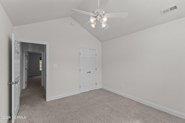 unfurnished bedroom with vaulted ceiling, light colored carpet, ceiling fan, and a closet