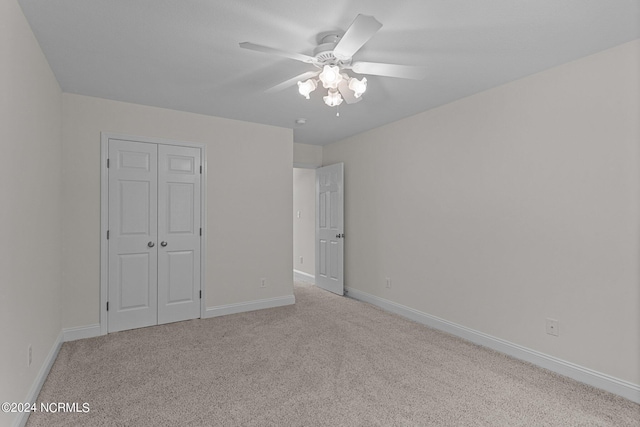 unfurnished bedroom featuring light colored carpet, ceiling fan, and a closet