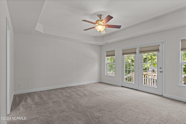 unfurnished room featuring light carpet, ceiling fan, and a tray ceiling