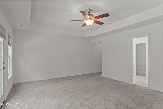 carpeted empty room with ceiling fan and a tray ceiling