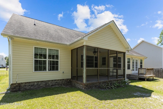 back of house featuring a wooden deck, a yard, and a sunroom