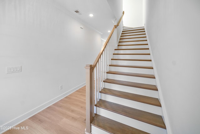 staircase with wood finished floors, baseboards, visible vents, and recessed lighting