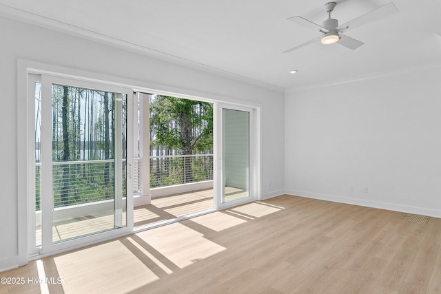 spare room with visible vents, baseboards, ornamental molding, a ceiling fan, and light wood-style floors