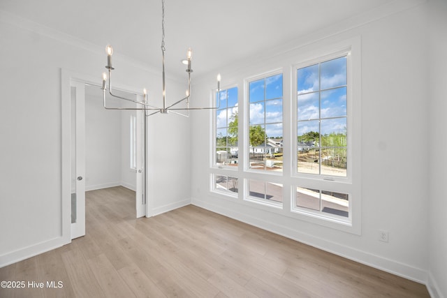 unfurnished dining area with crown molding, baseboards, light wood-type flooring, and a chandelier