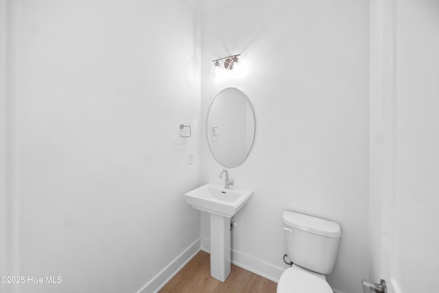 bathroom with toilet, wood finished floors, and baseboards
