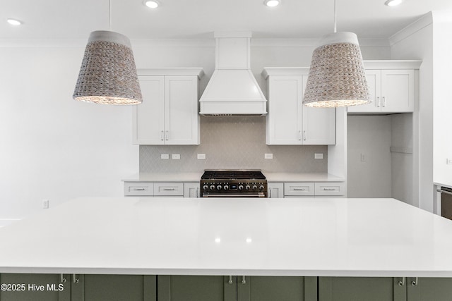 kitchen with premium range hood, stainless steel stove, light countertops, and ornamental molding
