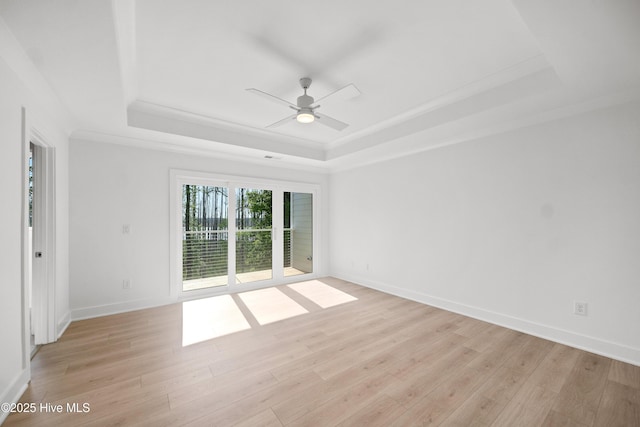 empty room with light wood finished floors, ceiling fan, baseboards, and a raised ceiling