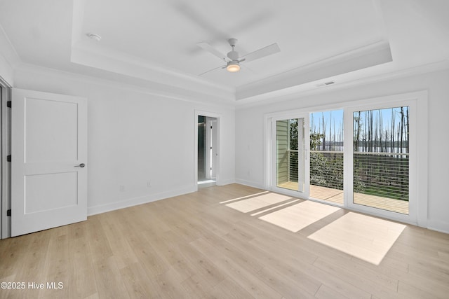 empty room featuring visible vents, light wood-type flooring, a raised ceiling, and ceiling fan