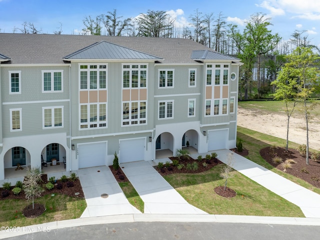 view of front of property featuring metal roof, driveway, an attached garage, and a front lawn