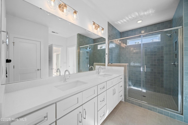 bathroom featuring a sink, a shower stall, double vanity, and tile patterned flooring