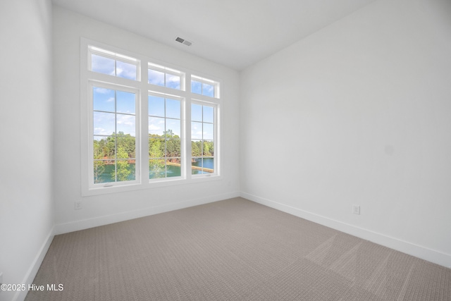 empty room featuring light carpet, visible vents, and baseboards