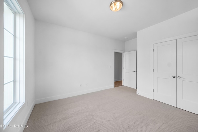 unfurnished bedroom featuring baseboards, multiple windows, and carpet
