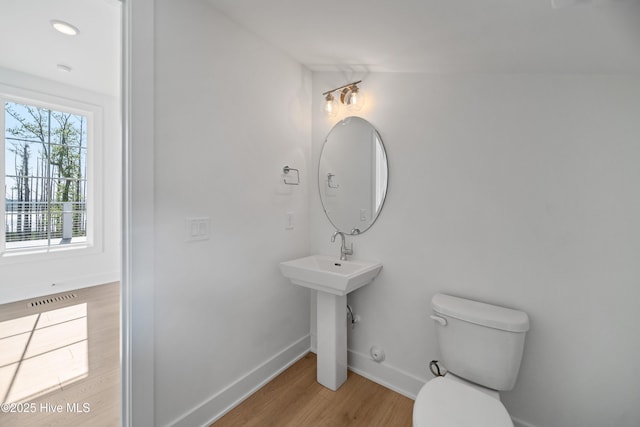 half bathroom featuring toilet, visible vents, baseboards, and wood finished floors