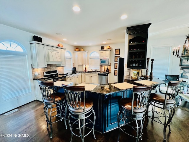 kitchen featuring sink, white cabinetry, appliances with stainless steel finishes, a breakfast bar area, and dark hardwood / wood-style flooring