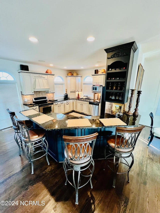 kitchen with a kitchen breakfast bar, kitchen peninsula, dark hardwood / wood-style floors, and plenty of natural light