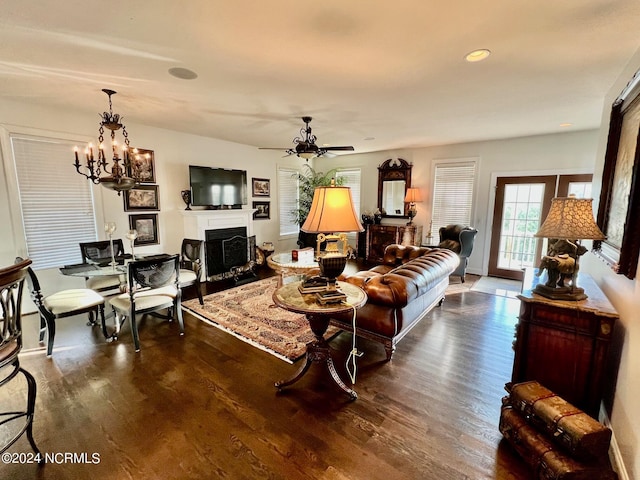 living room with ceiling fan with notable chandelier and dark hardwood / wood-style floors