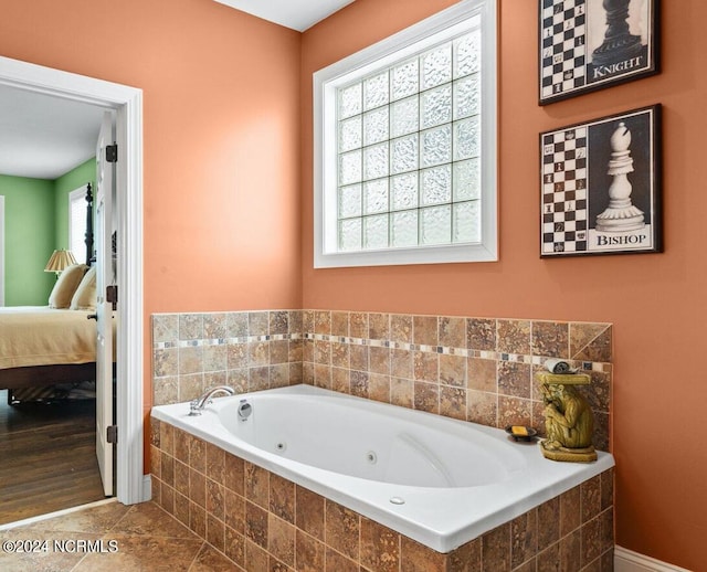 bathroom with a relaxing tiled tub, plenty of natural light, and tile patterned floors