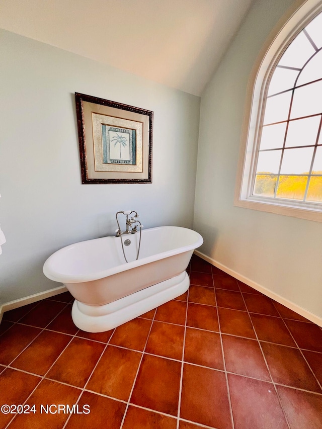 bathroom with a bath, lofted ceiling, and tile patterned floors