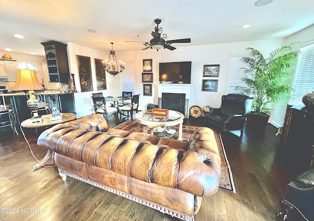 living room with ceiling fan with notable chandelier and hardwood / wood-style floors