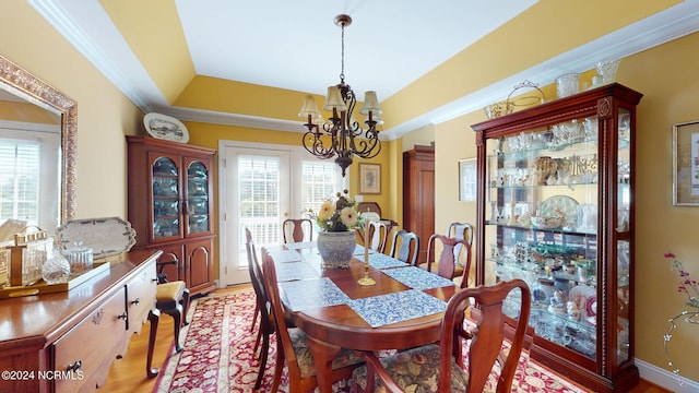 dining room featuring wood-type flooring, crown molding, a raised ceiling, and a notable chandelier