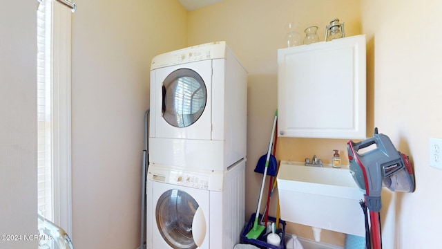 washroom with stacked washer and dryer, a sink, and cabinet space