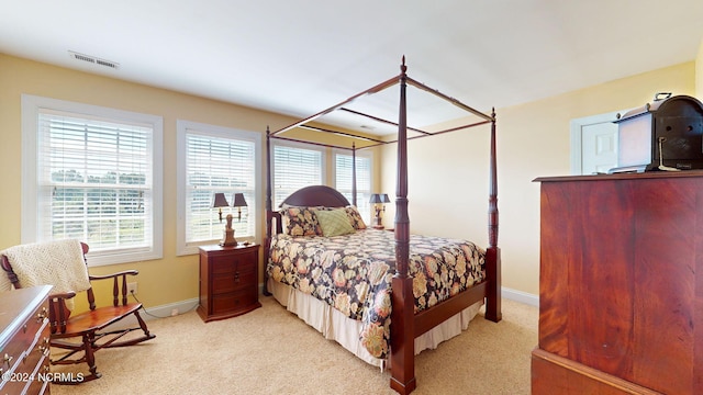 bedroom featuring light carpet, visible vents, and multiple windows