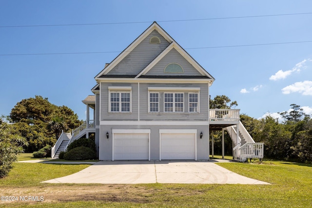 beach home featuring a front yard, driveway, stairway, and an attached garage