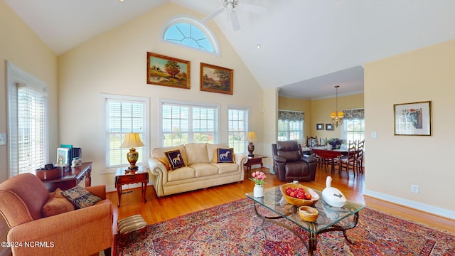 living room featuring light wood-type flooring, ceiling fan with notable chandelier, and high vaulted ceiling