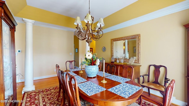 dining room with crown molding, an inviting chandelier, hardwood / wood-style flooring, and ornate columns